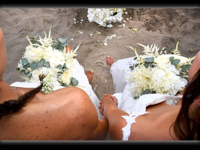 spose con piedi nella sabbia e bouquet in mano