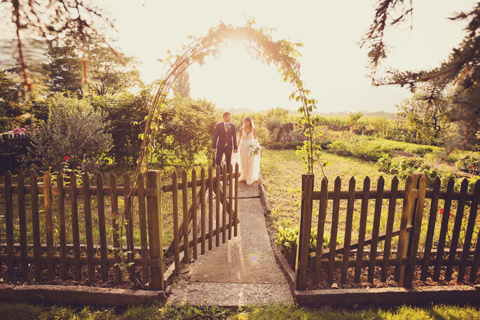 Hochzeitsfoto. Brautpaar vor Sonnenuntergang hinter Gartentürchen