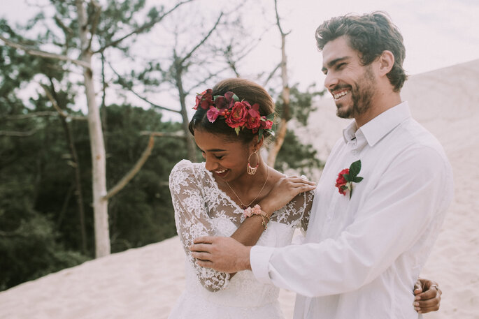 couple heureux qui a évaluer le budget avant le mariage sur une dune de sable mariée accessoire fleurs cheveux