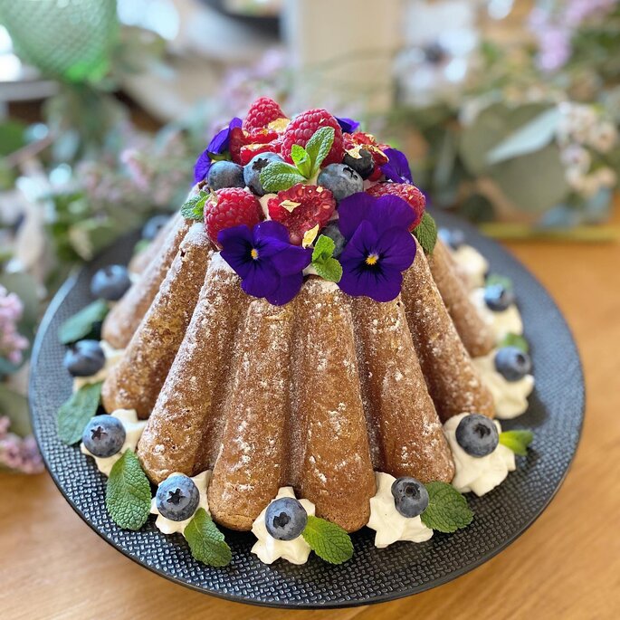 Gâteau de Savoie surmonté de fleurs et de myrtilles et framboises 