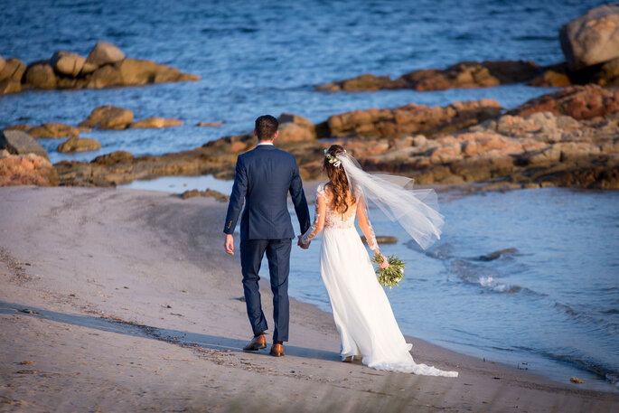 Des mariés marchent sur une plage 