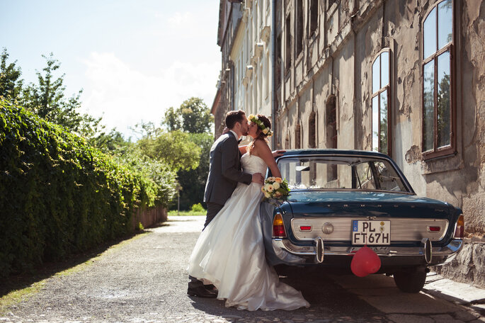 Casal de noivos apoiado em carro antigo