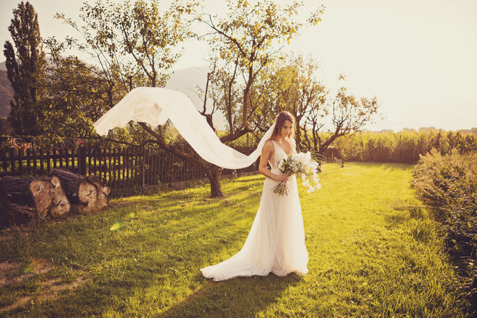 Hochzeitsfoto. Braut im Garten mit fliegendem Schleier